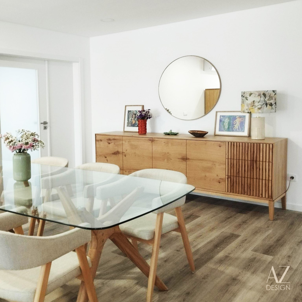 sala de jantar com mesa de vidro, cadeiras, comoda de madeira com vaso e quadros e espelho na parede