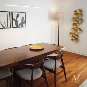 Sala de jantar com mesa de madeira, cadeiras, candeeiro e quadro na parede