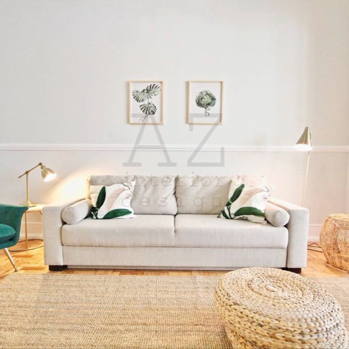 sala de estar com sofá branco e almofadas, dois candeeiros, dois quadros na parede e tapete